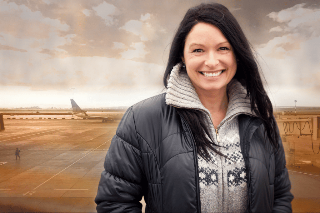 smiling woman with a plane behind her